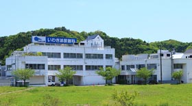 緑に囲まれた介護施設の外観。白い建物に青いロゴが目印。